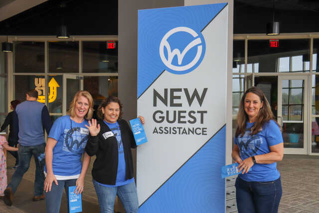 women volunteers standing by new guest signage