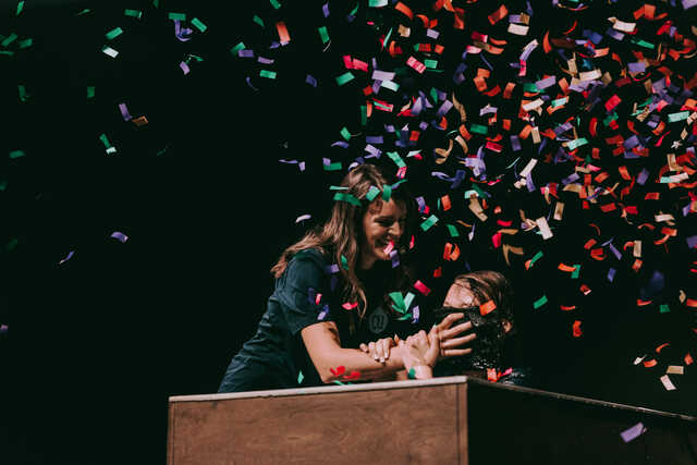 Woman baptizing middleschooler with confetti falling